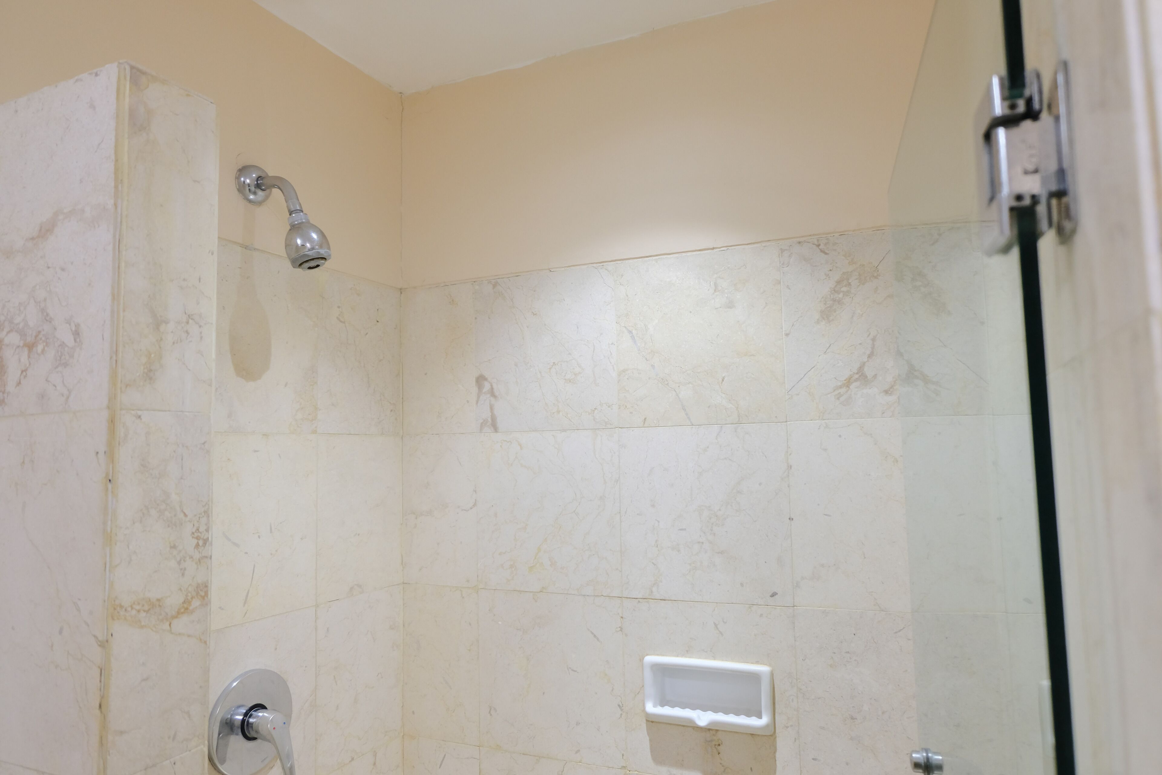 A bathroom with a shower, tiled walls, and a door.