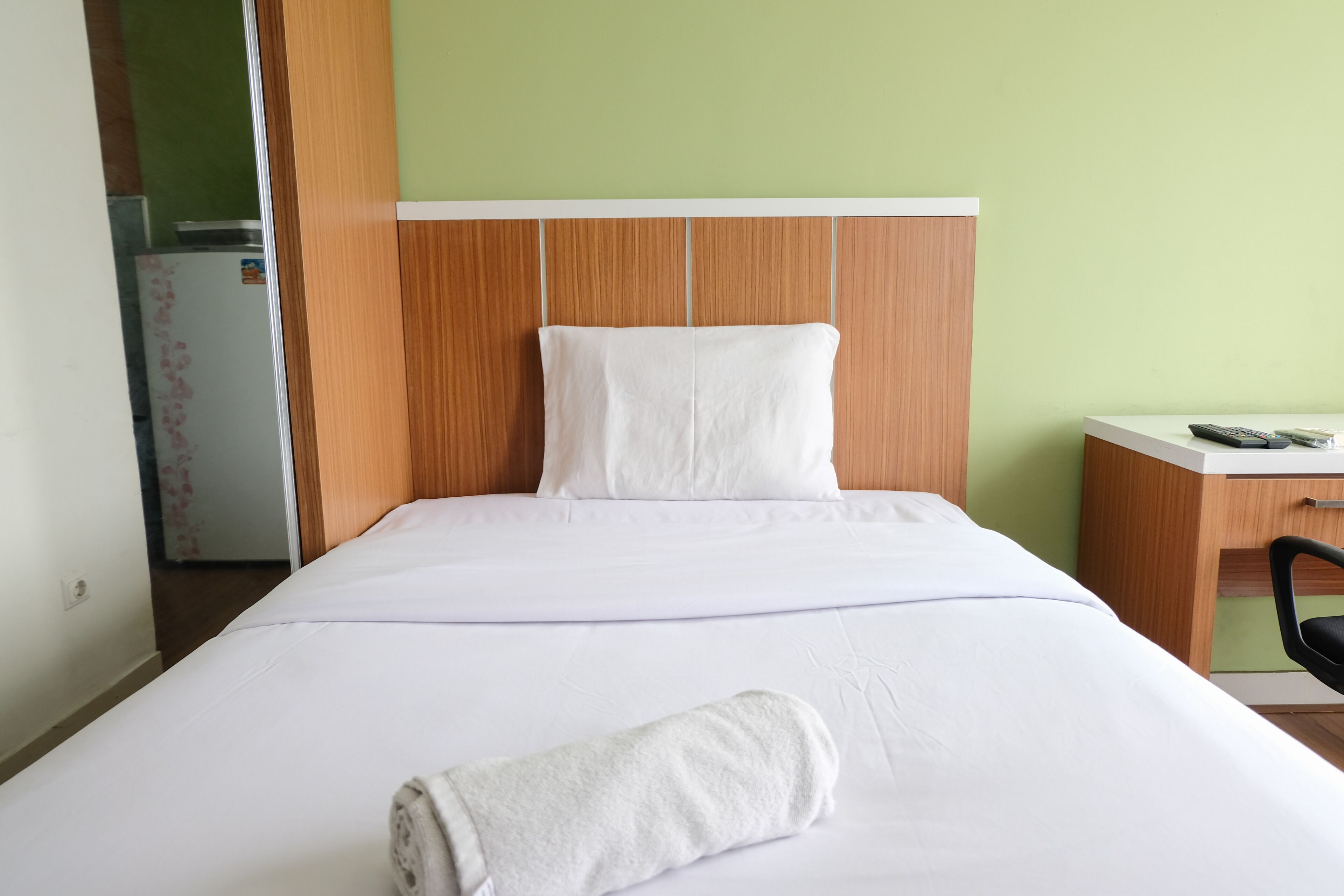 A hotel room with a bed, a desk, and a refrigerator.