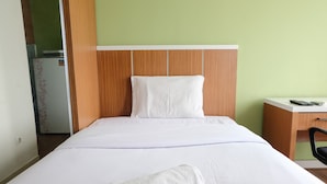 A hotel room with a bed, a desk, and a refrigerator. - Minimalist Studio at Harvard Jatinangor Apartment (Cileunyi)