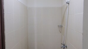 A small, tiled shower stall with a handheld showerhead and a wall-mounted faucet. - Minimalist Studio at Harvard Jatinangor Apartment (Cileunyi)