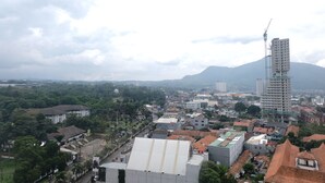 A cityscape with a prominent building under construction, surrounded by residential buildings and greenery. - Minimalist Studio at Harvard Jatinangor Apartment (Cileunyi)