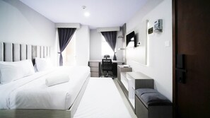 A hotel room with a large bed, a desk, a chair, a TV, and a wardrobe. - Nice And Comfy Studio At Grand Dharmahusada Lagoon Apartment (Surabaya)