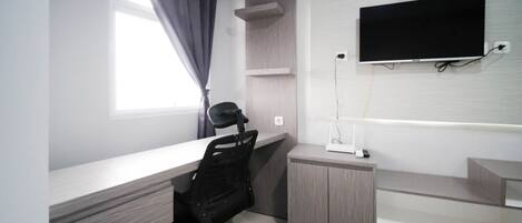 Un espace de bureau moderne comprenant un bureau, une chaise et un téléviseur à écran plat fixé au mur.