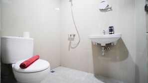 A small bathroom with a toilet, a sink, and a shower. - Nice And Comfy Studio At Grand Dharmahusada Lagoon Apartment (Surabaya)