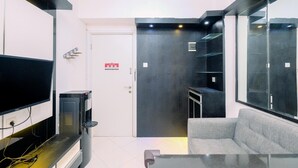 A modern living room with a flat-screen TV, a sofa, and a glass coffee table. - Best Deal And Modern 1Br Green Pramuka City Apartment (Jakarta)