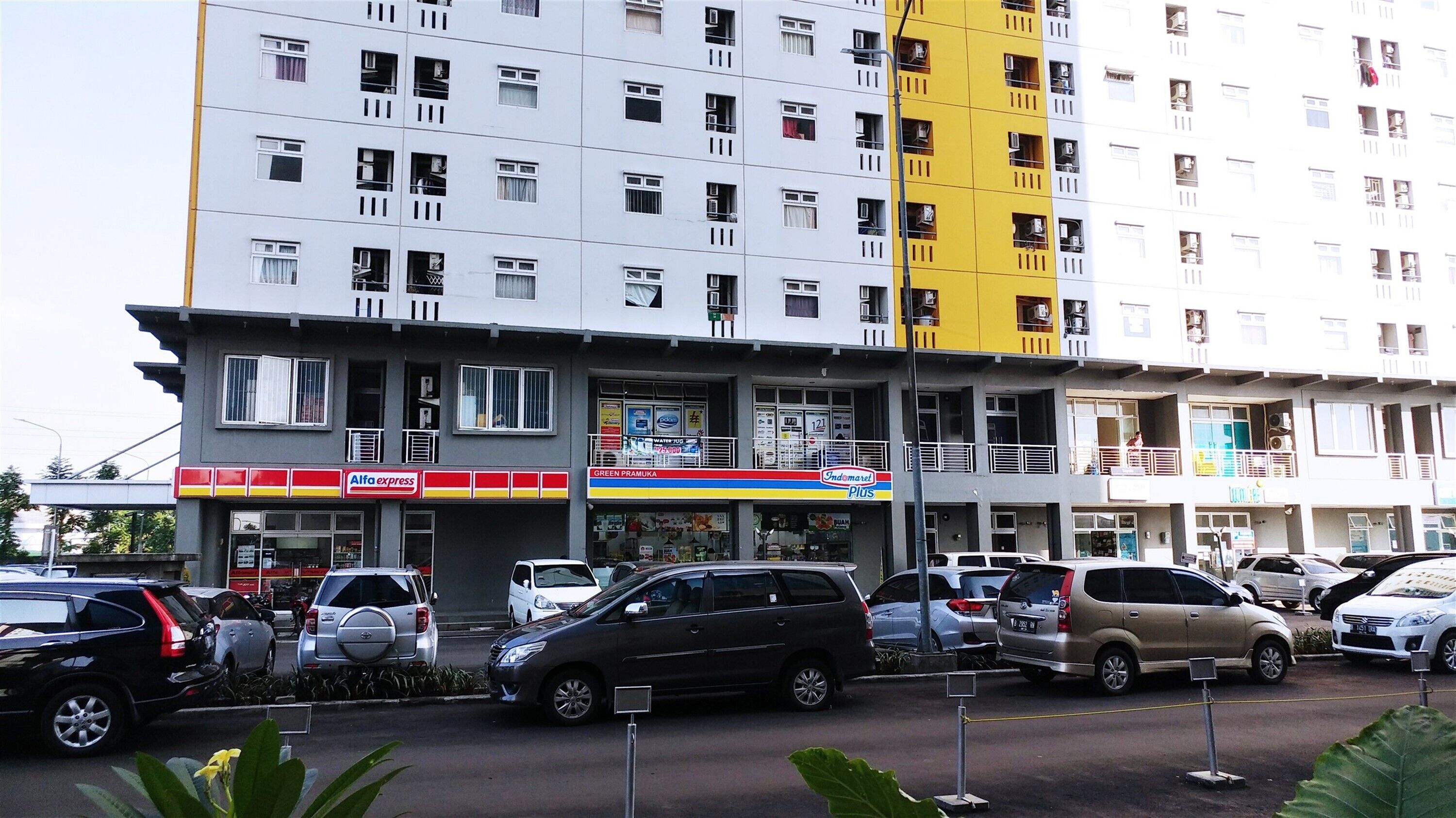 Un immeuble à plusieurs étages dont le rez-de-chaussée abrite des commerces, notamment une pharmacie et une épicerie.