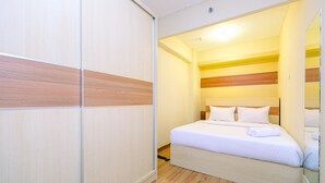 A bedroom with a bed, wooden floor, and a sliding door. - Best Deal And Modern 1Br Green Pramuka City Apartment (Jakarta)