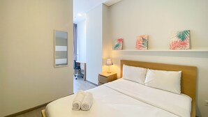 Et hotelværelse med en stor seng, et natbord med lampe og kunst på væggen.