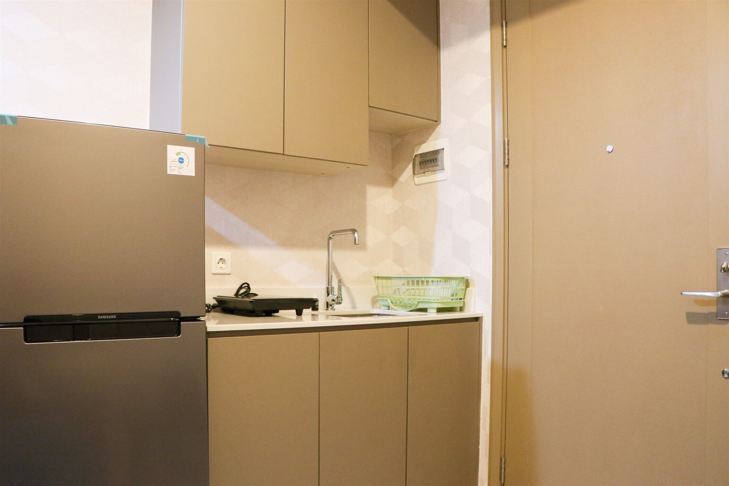 Una cocina con un refrigerador Samsung, un lavamanos y una cesta verde sobre la encimera.