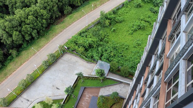 An aerial view of a building with a parking lot, green spaces, and a road. - Nice And Relaxing 1Br At Gold Coast Apartment (Jakarta)