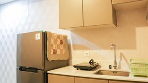 A kitchen with a stainless steel refrigerator, a sink, and a green dish rack. - Nice And Relaxing 1Br At Gold Coast Apartment (Jakarta)