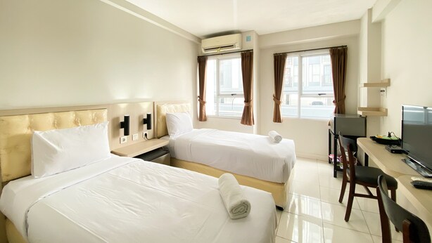 Una habitación de hotel con dos camas, un escritorio, una silla y un televisor.