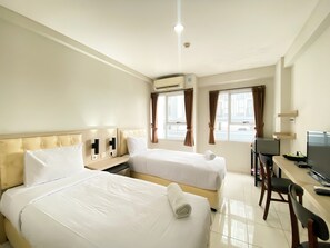 Ein Hotelzimmer mit zwei Betten, einem Schreibtisch, einem Stuhl und einem Fernseher.
