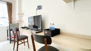 Habitación de hotel con televisión de pantalla plana, escritorio con computadora, dos sillas y un minibar.