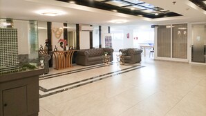 A spacious lobby with a modern design, featuring a seating area with sofas, a coffee table, and a decorative railing. - Minimalist Studio At De Prima Apartment (Medan)