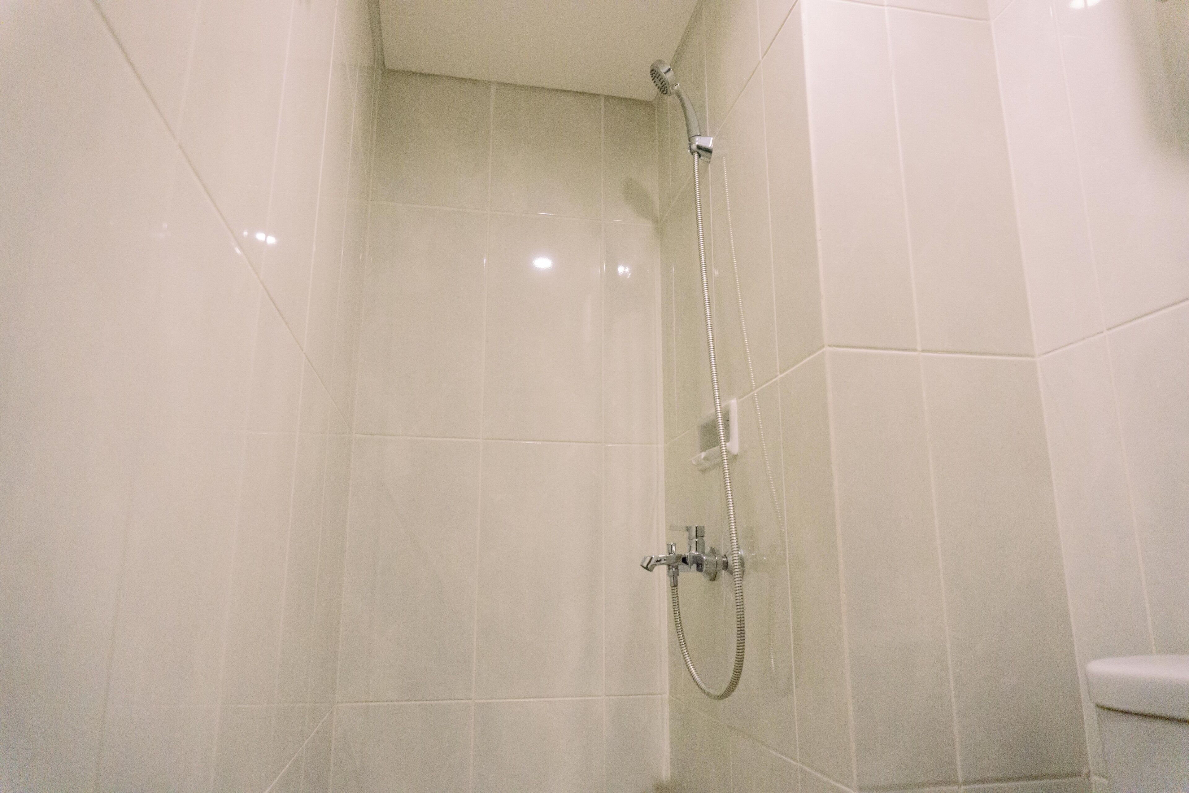 A shower area with a handheld showerhead and a wall-mounted faucet.