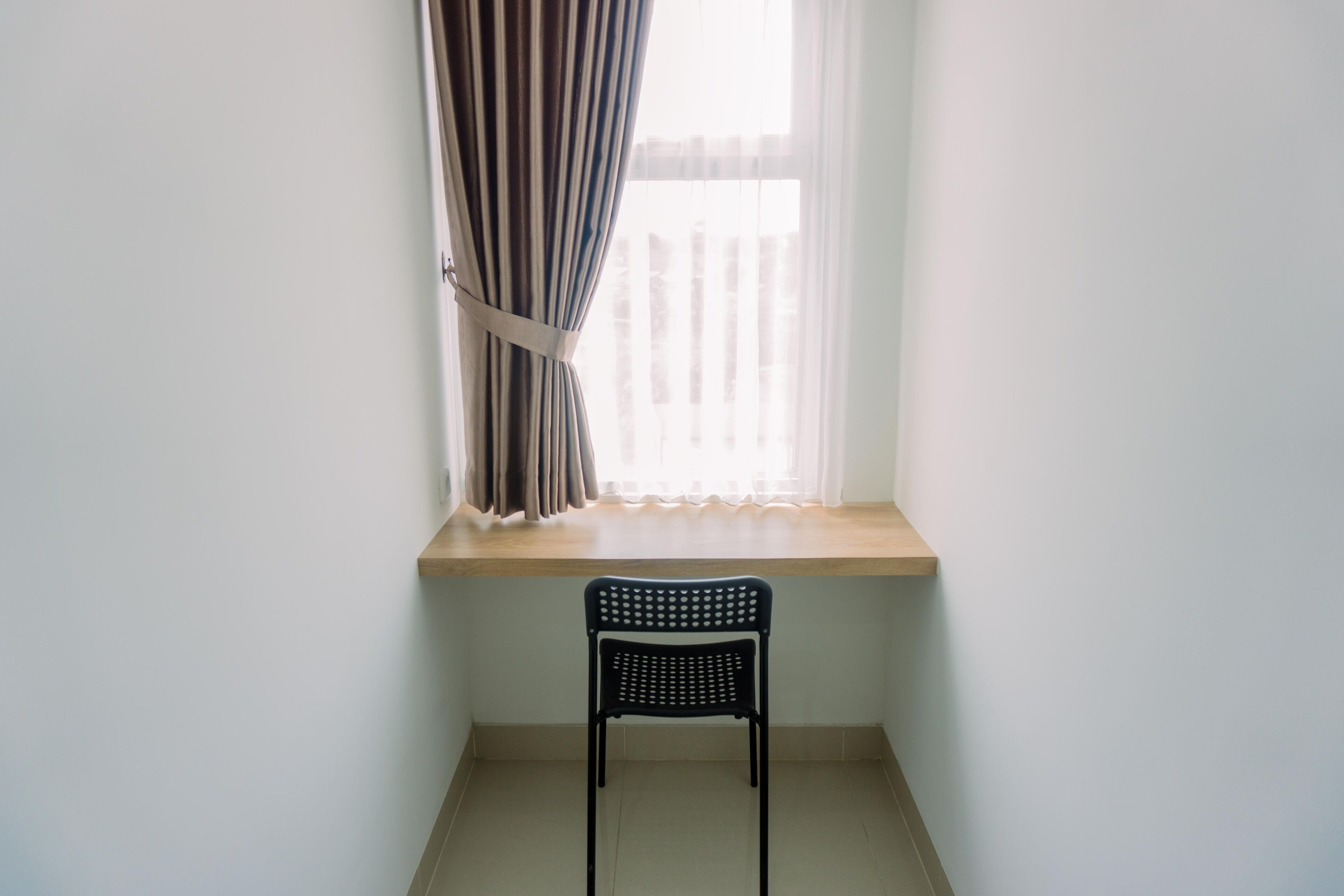 A room with a window, a chair, and a wooden ledge.