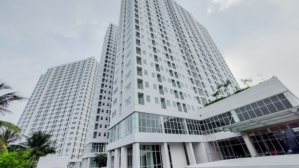 A high-rise building with a modern architectural design, featuring a prominent glass facade and a series of balconies. - Minimalist And Comfort 2Br Serpong Garden Apartment (Cisauk)