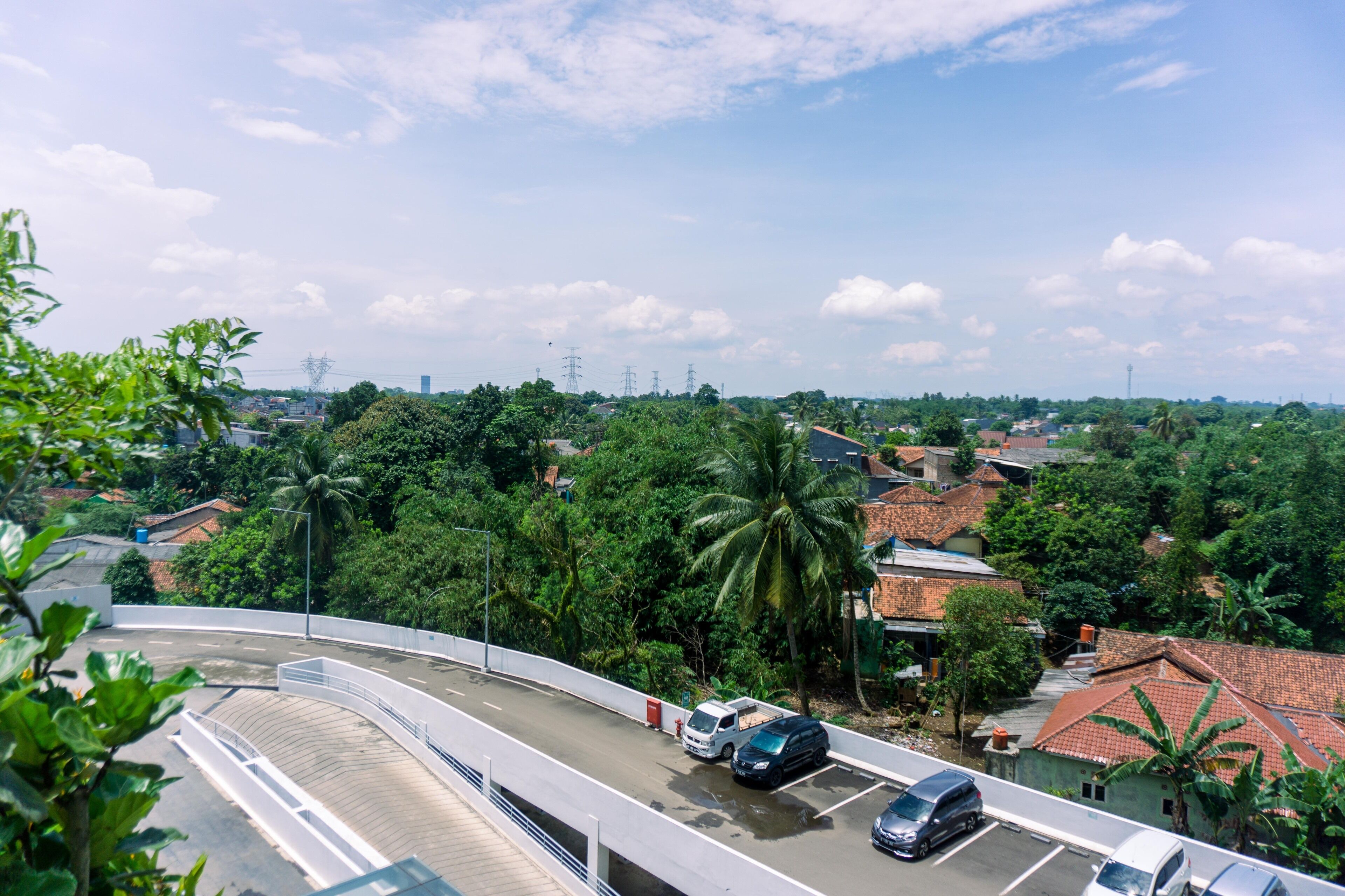 A curved road with vehicles, surrounded by lush greenery and residential buildings.