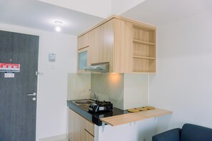 Cozinha compacta com fogão embutido, pia e prateleira superior de madeira.
