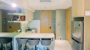 A modern kitchen with a central island, bar stools, a built-in oven, and a refrigerator.