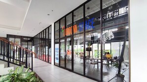 A modern indoor space with glass walls, a staircase, and indoor plants. - Cozy Stay Studio Cordova Edupartment Semarang Apartment (Semarang)