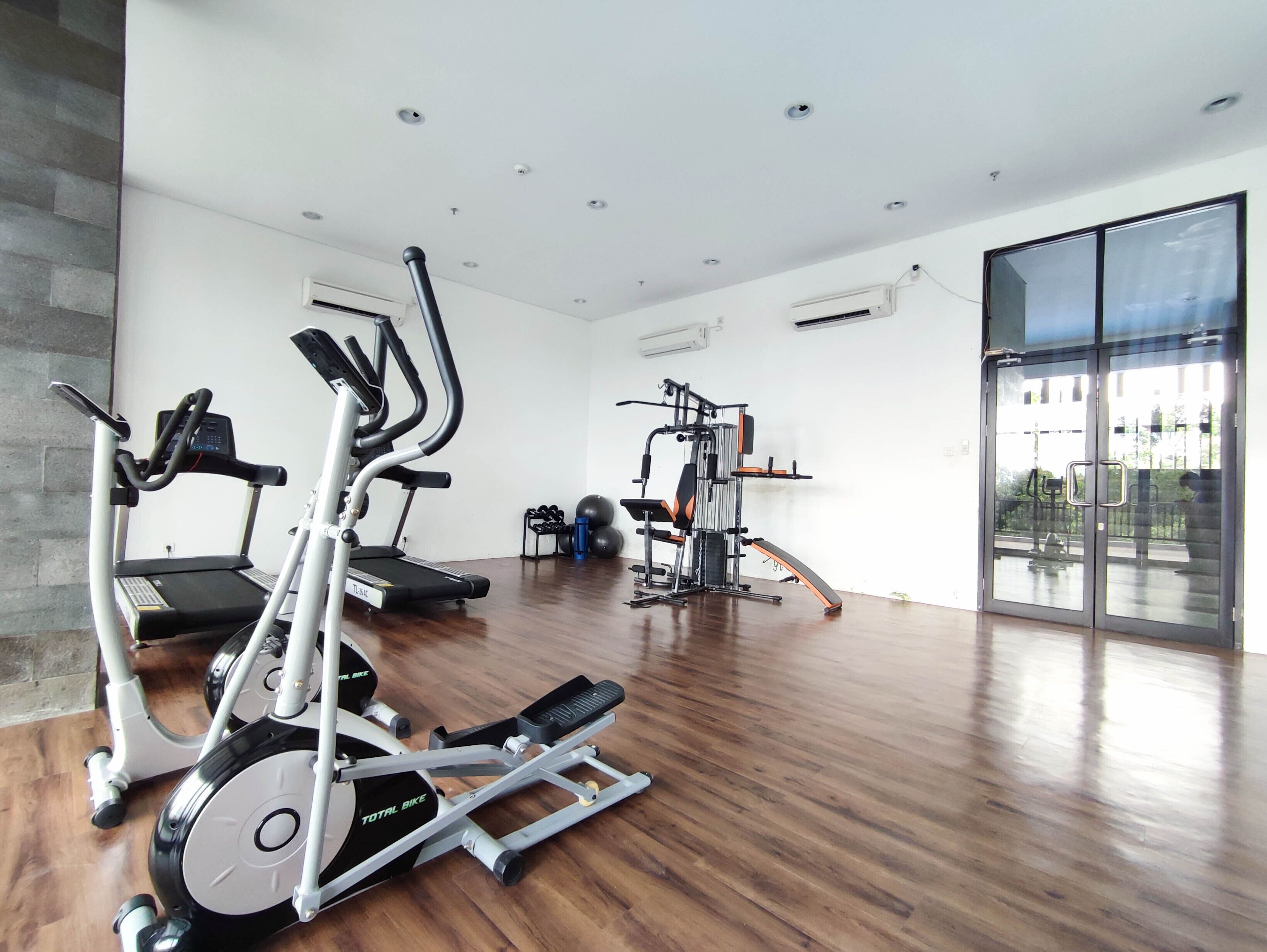 Een moderne sportschool met diverse fitnessapparaten, waaronder loopbanden, elliptische trainers en krachtapparaten.
