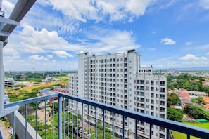 Stunning high-rise building with a grid-like facade and multiple balconies, set amidst lush greenery and other residential structures.