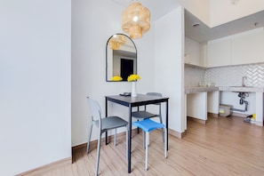Enjoy meals in this stylish dining area with a table for two, a mirror above, and a kitchen nearby.