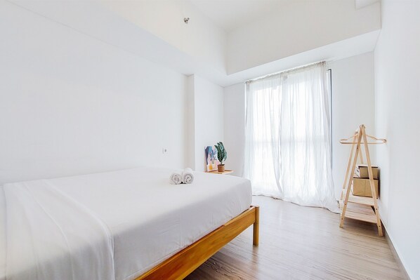 A minimalist bedroom with a wooden bed, a bedside table with a plant, and a wooden ladder against the wall.