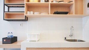 Eine moderne Küche mit integriertem Spülbecken, Holzschränken und einer Arbeitsplatte. Es ist ein kleiner Wasserhahn und eine schwarze Box mit dem Aufdruck 'Travelio' vorhanden.