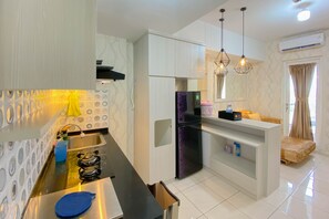 A modern kitchen with a black stove, a purple refrigerator, and a white countertop. - Spacious And Homey 3Br At Springlake Summarecon Bekasi Apartment (Bekasi)