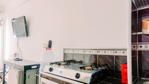 Eine Küche mit Gasherd, Mikrowelle und einem an der Wand befestigten Fernseher.