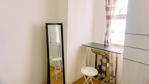 Ein kleiner, kompakter Raum mit Spiegel, Hocker und Tisch.