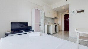 Une chambre d’hôtel comprenant un lit, une télévision, un bureau, une kitchenette et une salle de bain.