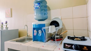 A kitchen with a water dispenser, a dish rack, and a stove. - Comfortable And Modern Studio Serpong Greenview Apartment (South Tangerang)