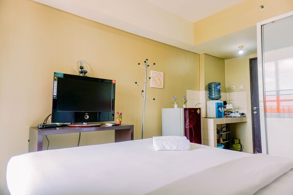 Une chambre d’hôtel comprenant un lit, un bureau avec une télévision, un porte-manteau et un distributeur d’eau.