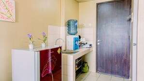 A compact kitchen with a refrigerator, sink, and a large water dispenser. - Comfortable And Modern Studio Serpong Greenview Apartment (South Tangerang)