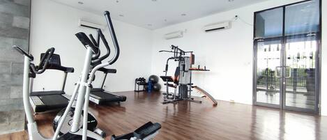 Un gimnasio moderno con una variedad de equipos de ejercicio, incluyendo cintas de correr, elípticas y máquinas de pesas.