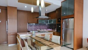Une cuisine moderne avec des meubles en bois, une table à manger en verre et des appareils électroménagers en acier inoxydable.