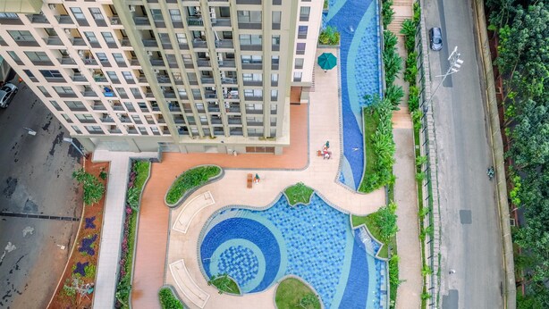 A high-rise building with a central courtyard featuring a circular water feature, surrounded by greenery and seating areas. - Minimalist And Good Deal Studio Transpark Cibubur Apartment (Depok)