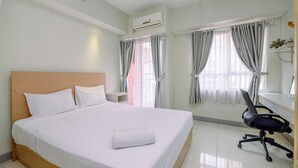 A hotel room with a large bed, a desk with a chair, and a window with curtains. - Cozy And Simply Look Studio Room Taman Melati Margonda Apartment (Depok)