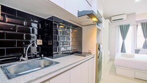 Una cocina moderna con salpicadero negro, pileta de acero inoxidable y muebles color blanco.