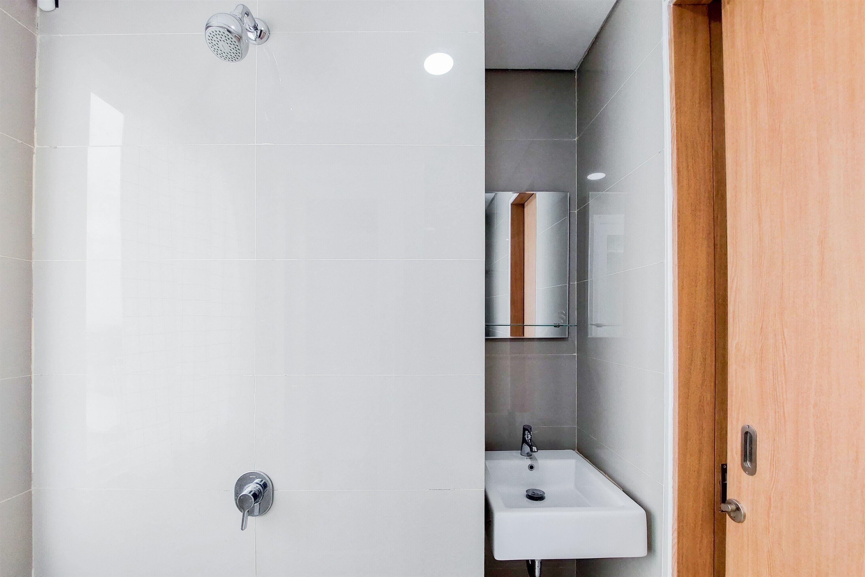 A modern bathroom with a shower, a sink, and a wooden door.