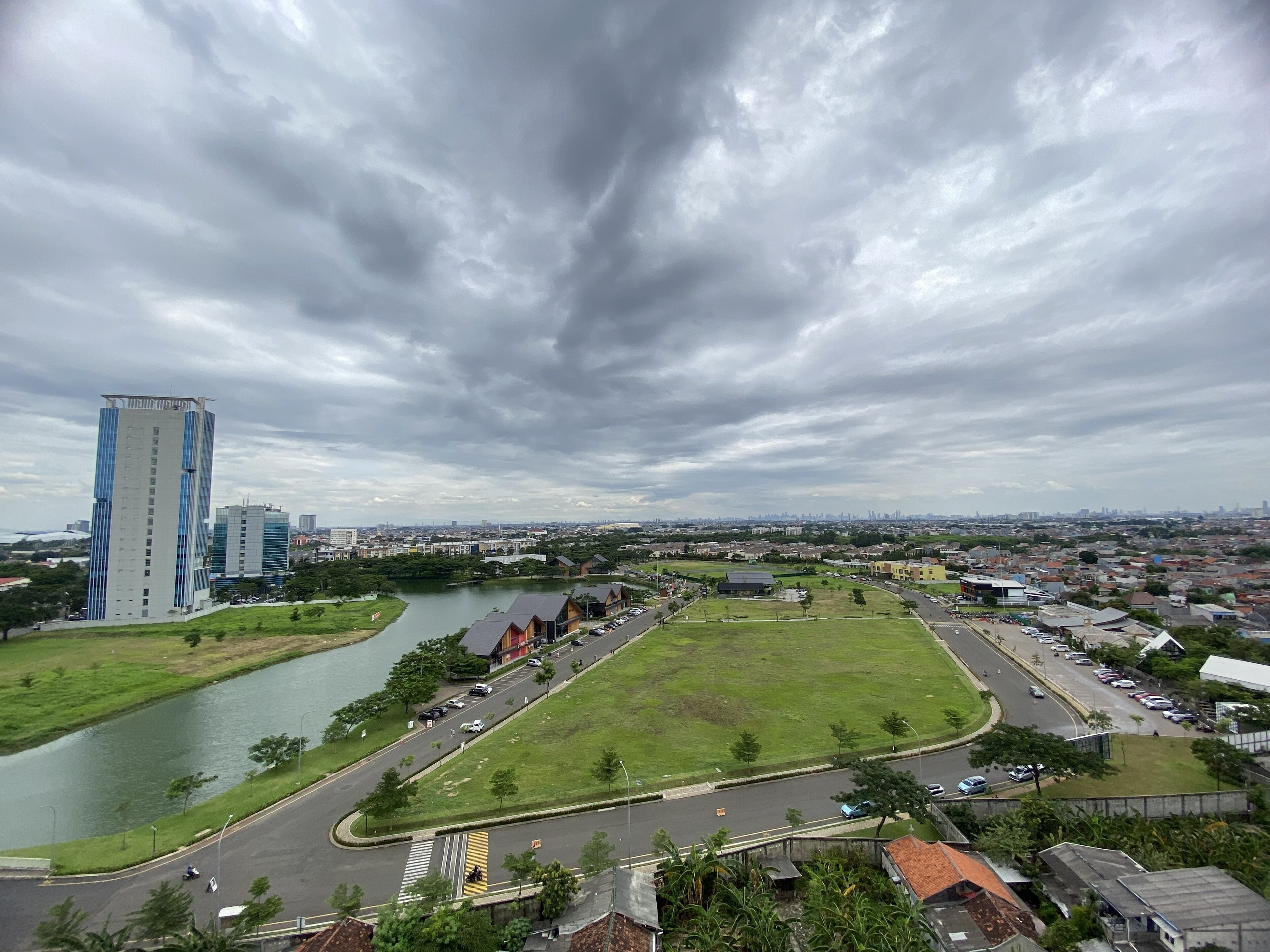 A cityscape with a river, a large open grassy area, and modern buildings including a tall skyscraper.