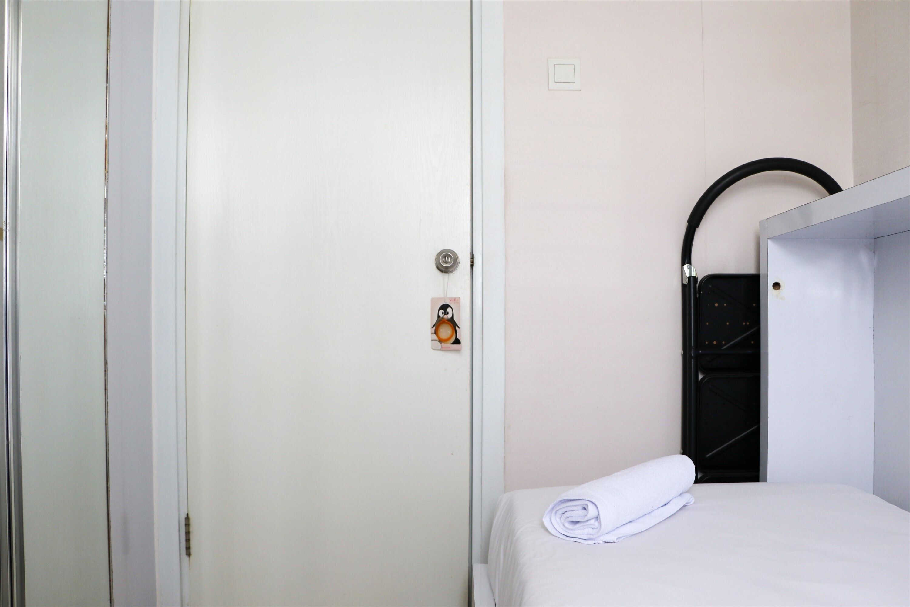 A hotel room with a bed, a white door, and a black circular object on the wall.