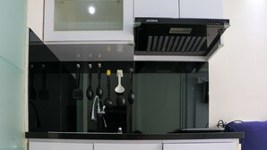 Une cuisine dotée d’une hotte noire, d’un four à micro-ondes et de divers ustensiles suspendus au-dessus de l’évier.