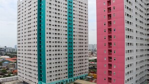 Un immeuble de grande hauteur aux couleurs vives, avec une prédominance de teintes turquoise et rose, doté de nombreux balcons et d’une façade ornée d’une grille dense de fenêtres.