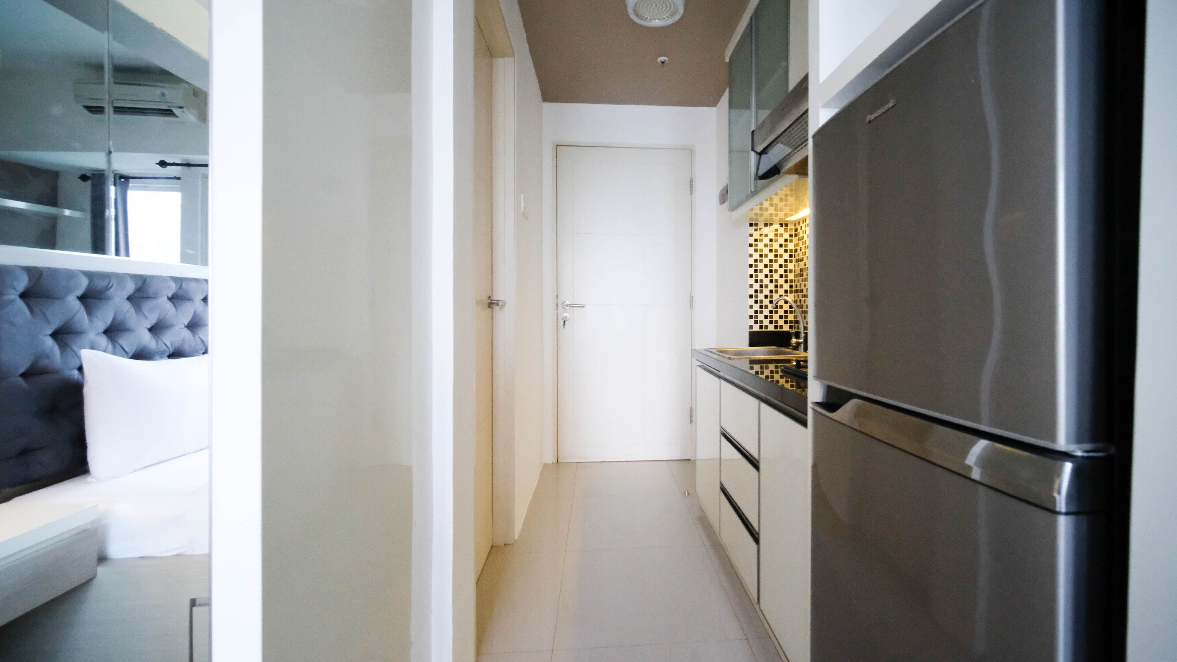 A modern kitchen with a stainless steel refrigerator, a built-in oven, and a tiled backsplash.