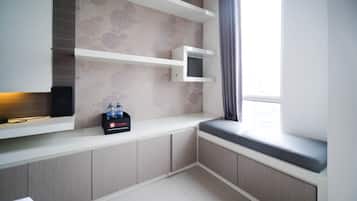 A modern kitchenette with built-in appliances, a flat-screen TV, and a water dispenser.